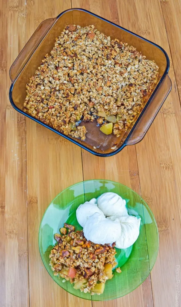 pan of apple crumble with a serving on a plate with ice cream