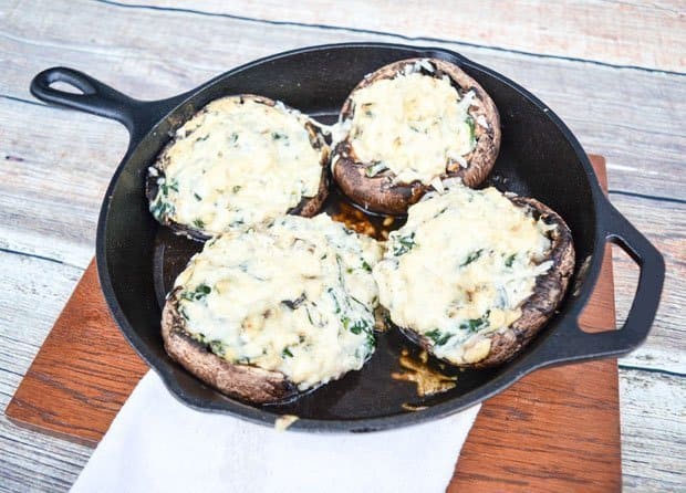 cast-iron skillet with four baked mushroom tops