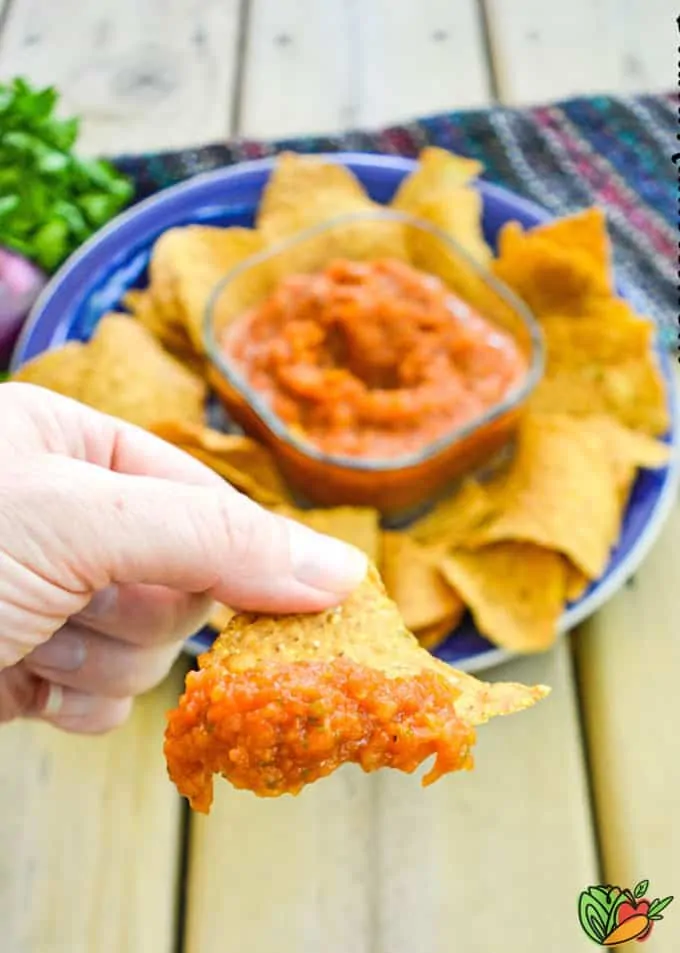 hand holding chip with salsa on it
