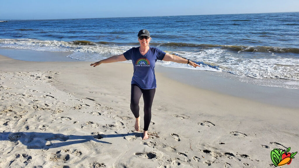 woman on the beach in front of the ocean taking an exercise class
