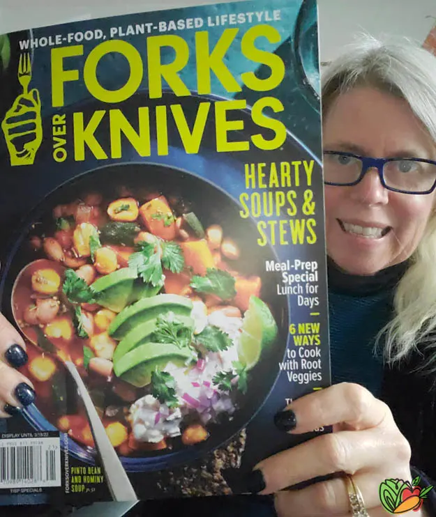 woman holding a copy of the Forks Over Knives magazine